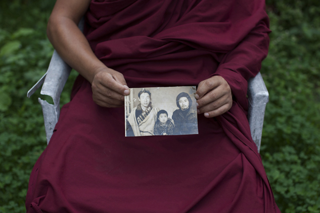 Tibetan monk Dorjee, 38, displays a photograph of his father, left, and himself, center, taken in Tibet, in Dharamsala, India. Dorjee said he held back his tears when he spoke with his parents on the phone after a separation period of 27 years. He exchanged a few words with his father but said his mother fainted on hearing his voice.